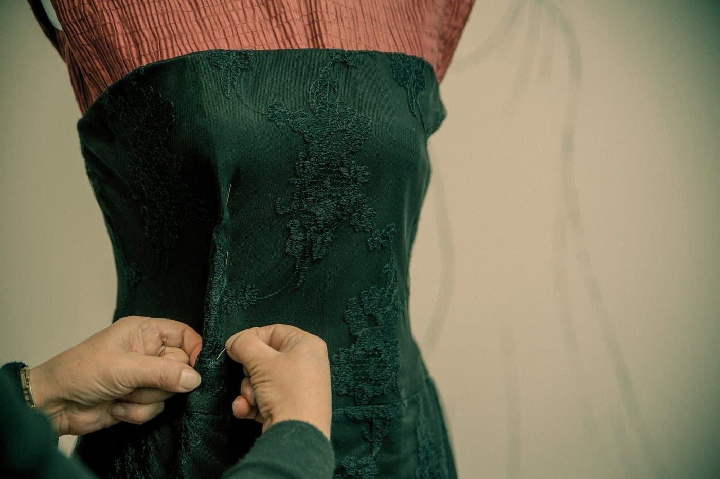Mâini care cos broderie florală pe un manechin